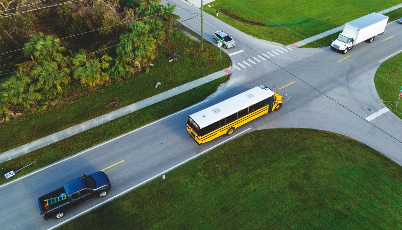 School Zone with Yellow School Bus and a speed limit sign that has been knocked down, showing the risk of school zone safety issues.